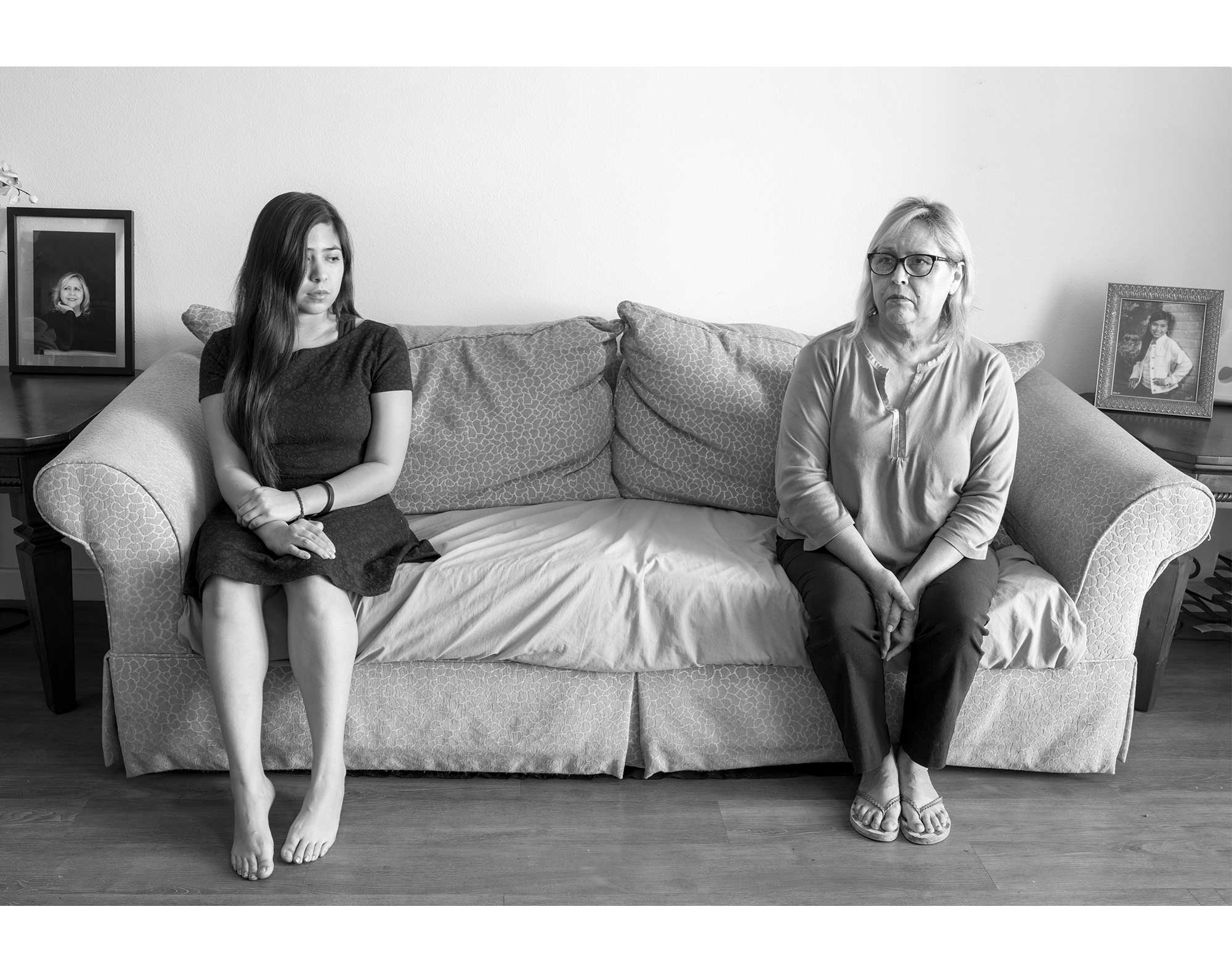 A mother and daughter sit on opposite ends of a couch.